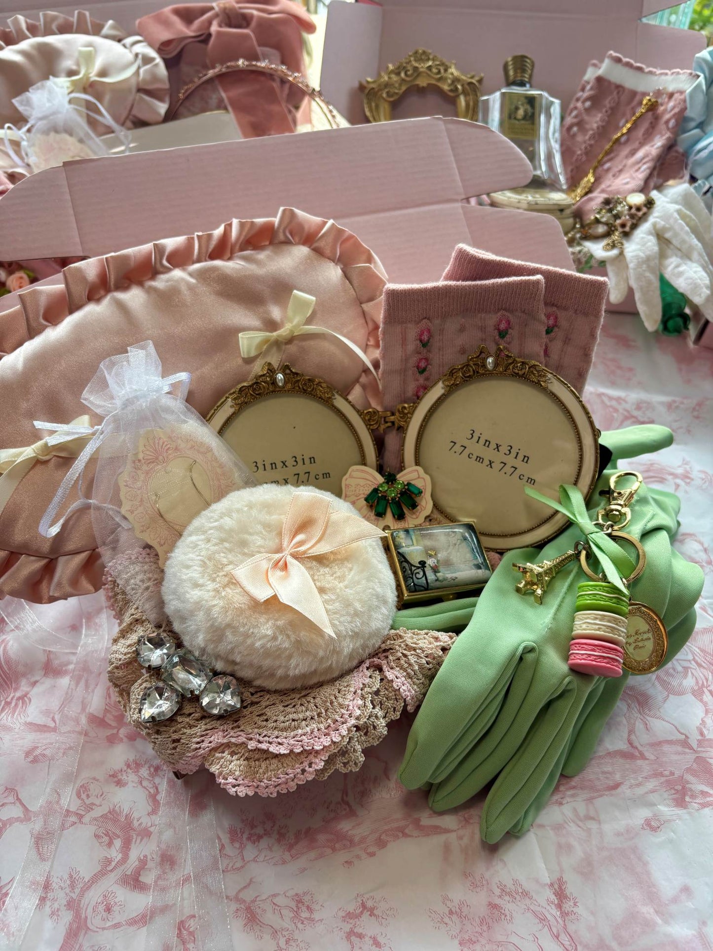 Collection of decorative vintage items including a round picture frame, powder puff, green gloves, sleep mask and trinket box